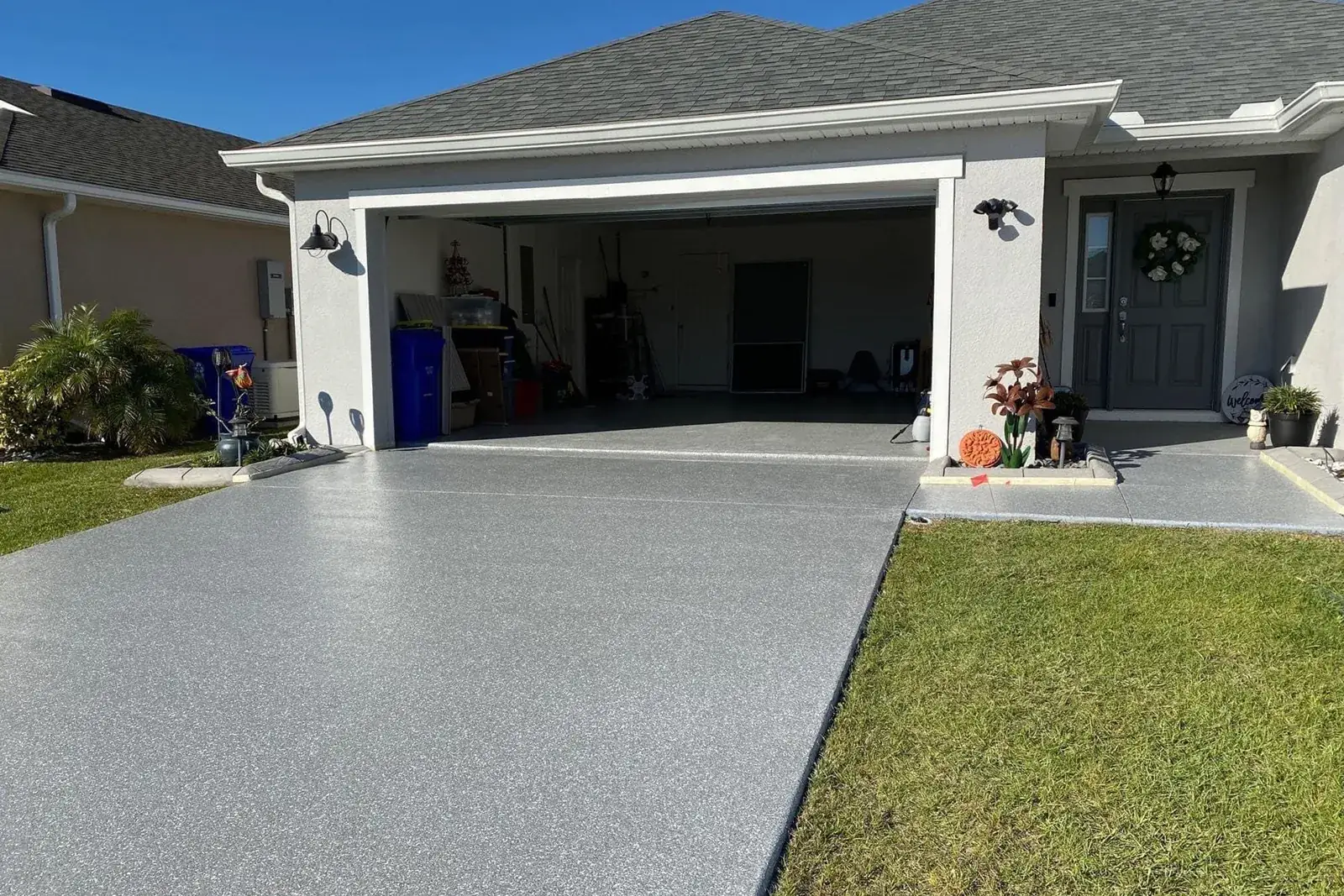 Concrete driveway with a fresh gray flake coating leading to an open two-car garage