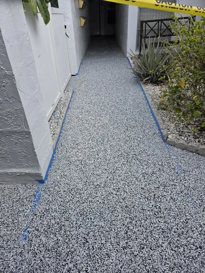 Fresh gray full-broadcast flake epoxy coating on a condo walkway in Pinellas County