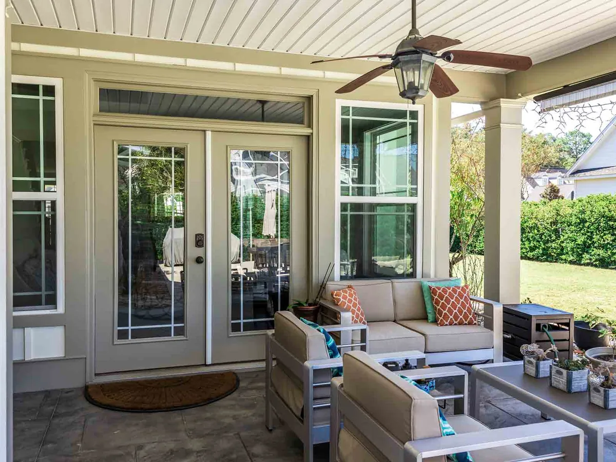 Covered lanai with a patterned concrete floor, outdoor seating and a ceiling fan